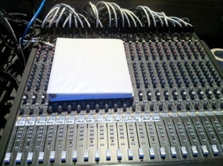Audio mixing console with actor mic channels and a cue script.