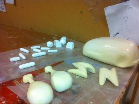 Process shot of a fake food project. Parts of a chicken are carved from foam and various vegetables are laid out.