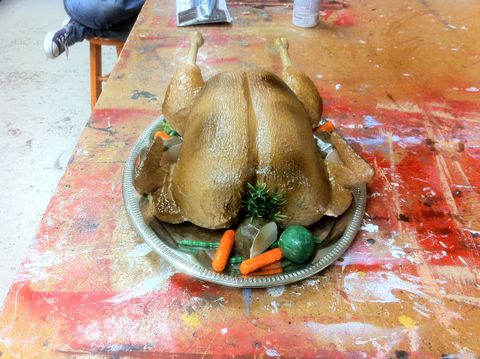 Fake roasted chicken on a platter with carrots, potatos, brussel sprouts, and green beans.