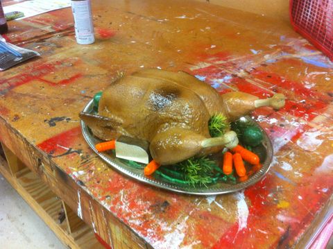 Fake roasted chicken on a platter with carrots, potatos, brussel sprouts, and green beans.