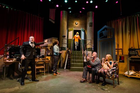 The director enters from up center to meet the actors. The actors are relaxing back stage.