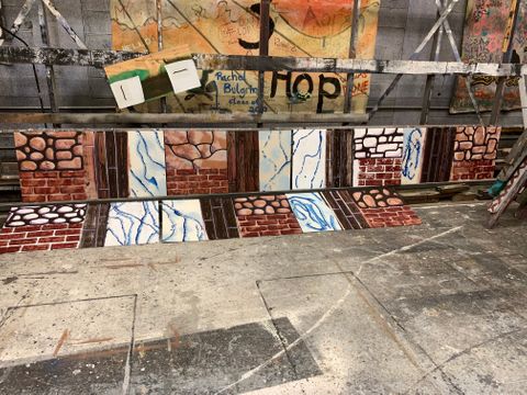 Collection of student scenic painting samples. Each sample has a faux wood, stone, brick, and marble texture painted on it.